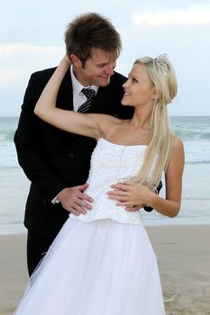 Pretty blond bride and her groom at the sea shore