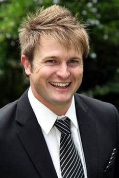 Handsome laughing young bridegroom in a black suit and tie