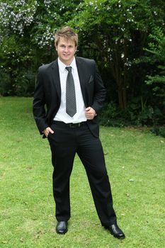 Handsome young bridegroom in a black suit and tie