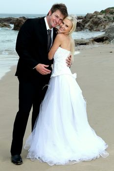 Pretty blond bride and her handsome groom at the sea shore