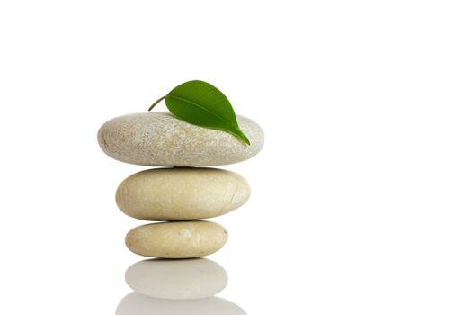 Spa stones and green leaf, isolated on white background.