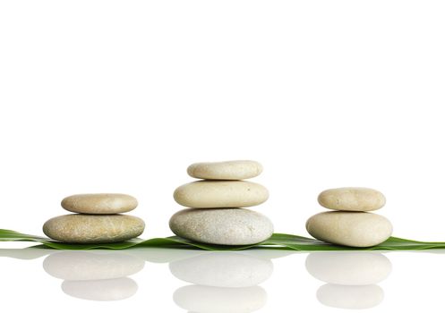 Spa stones and green leaf, isolated on white background.