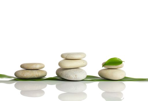 Spa stones and green leaf, isolated on white background.