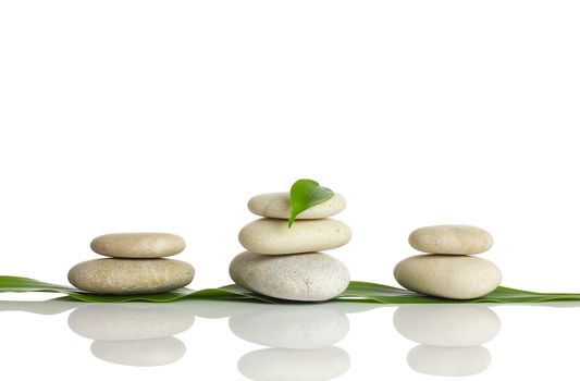 Spa stones and green leaf, isolated on white background.