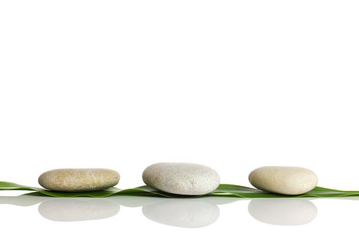 Spa stones and green leaf, isolated on white background.