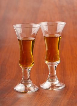 Two little glasses with liquor, over wooden background