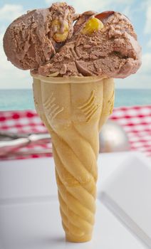 Ice cream cone over a white plate, with sea on the background