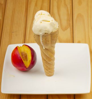 Ice cream cone on a white plate with a peach