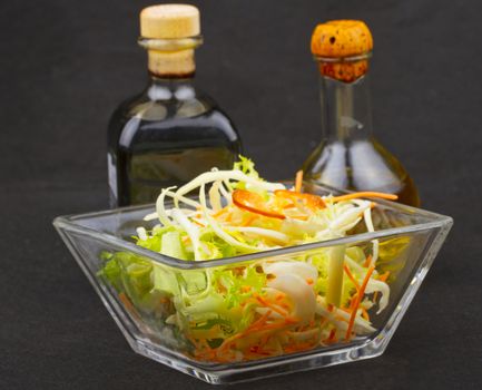 Glass cup of salad with vinegar and oil on the background