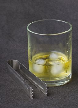 Whisky with ice over a black background, with an ice pick