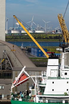 Close up view of ship at terminal with industrial buildings and windmills in background