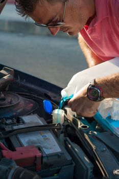 Man refilling an engine with blue  fluid