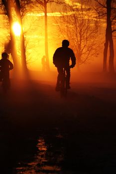 Father and son riding through misty sunset