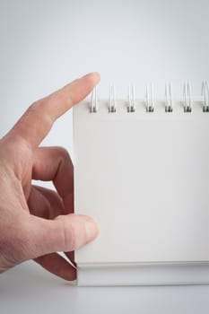 Hand holding a blank note pad on a white background