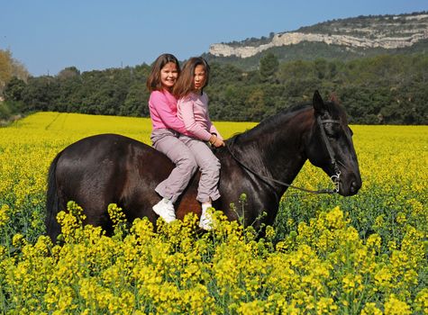 twins sisters horseback riding a black stallion