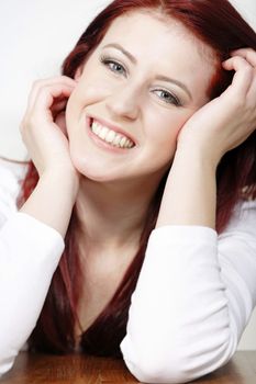 Beautiful young woman resting on a coffee table in front of sofa at home.