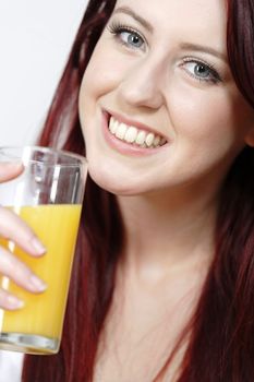 Smiling happy young woman with a fresh glass of Orange juice during breakfast.