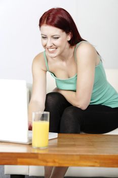 Happy smiling woman chatting with friends on a laptop at home on the sofa