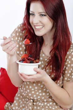 Happy smiling young woman enjoying a fresh bowl of fruit for breakfast.