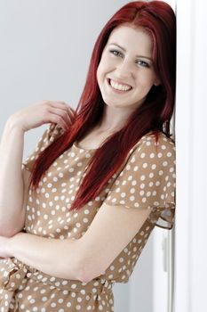 Beautiful happy young woman in a summer dress leaning against a wall.