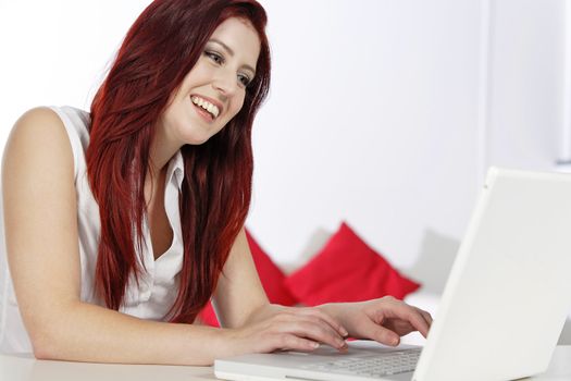 Happy young woman using a laptop at home