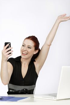 Professional young woman receiving good news on her mobile at work