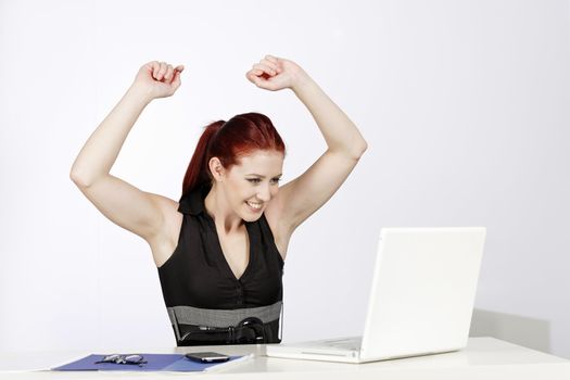 Professional young woman celebrating at work in her office