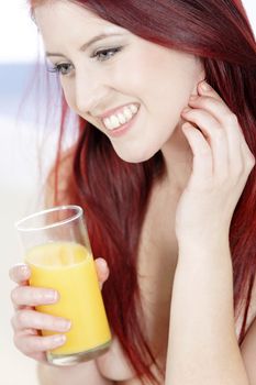 Beautiful woman drinking fresh Orange juice on her sofa at home