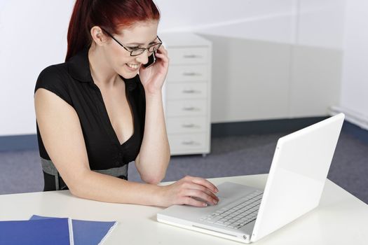 Beautiful young woman talking on her mobile phone at work