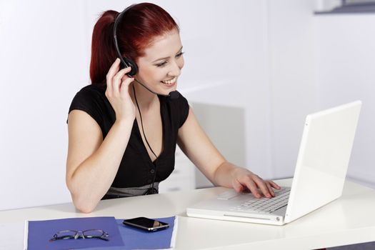 Professional woman talking on a headset in her office at work