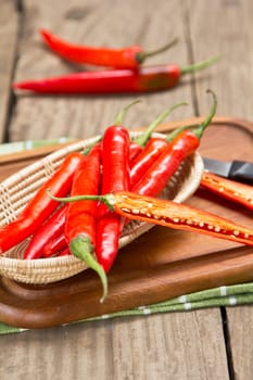 Red chilli in a small basket on chopping board