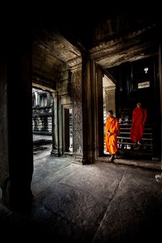 Unidentified buddhist monks walk in the ruin of Angkor. The monastery is still use as part of worship sacred place.