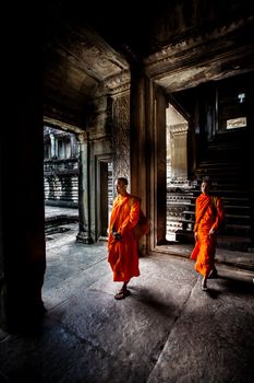 Unidentified buddhist monks walk in the ruin of Angkor. The monastery is still use as part of worship sacred place.