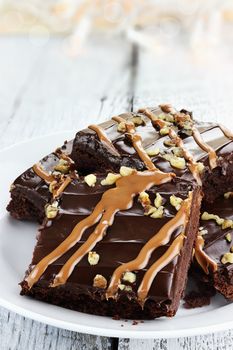 Close up plate of brownies with nuts and caramel sauce.