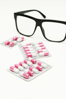 Capsules and pills packed in blisters and Glasses isolated on white.