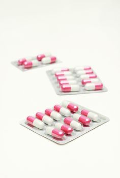 Capsules and pills packed in blisters isolated on white.