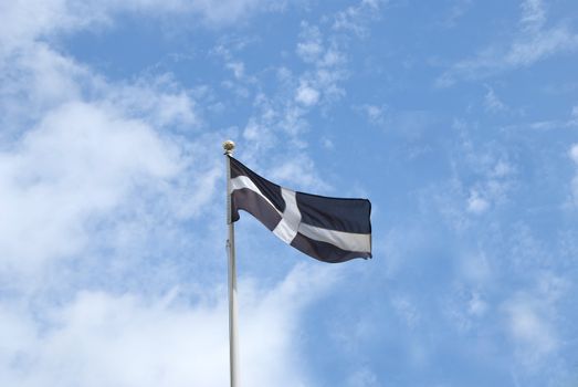 The Flag of Cornwall England flying in the wind under a blue sky