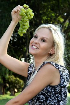 Lovely pretty blonde girl with a big bunch of green grapes