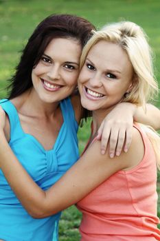 Two gorgeous smiling young women friends sharing a joke