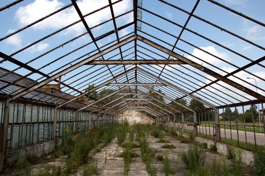 old abandoned greenhouse without windows against blue sky