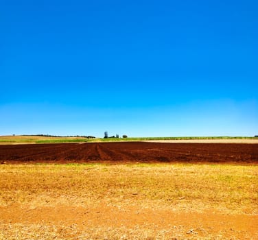 Cultivated ploughed field in farm agriculture area with blue sky