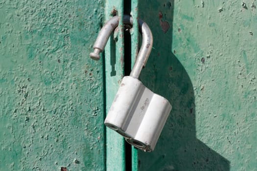 Big padlock on a green metal gate 