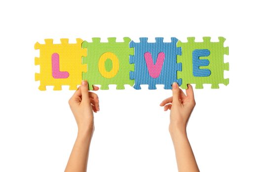 teacher holding in the hand the amusing colored educational puzzles with the word love