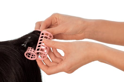hairdresser makes curls on the woman's black hair