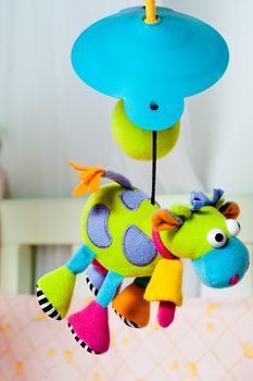 Colorful turning cow baby toy over the bed