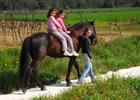 twins sisters horseback riding a black stallion