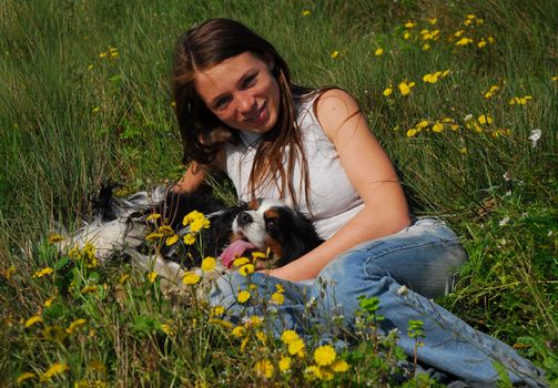 young teenager laid down in the grass with her cavalier king charles