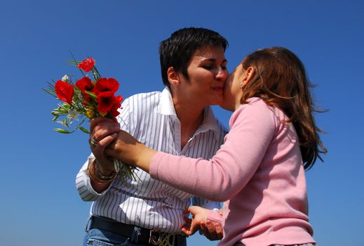 a little girl giving flowers to her mother