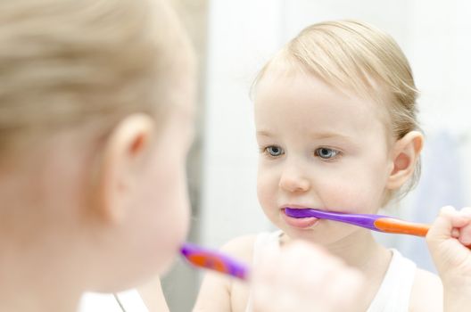 Little girl brushing her teeth in bathroom