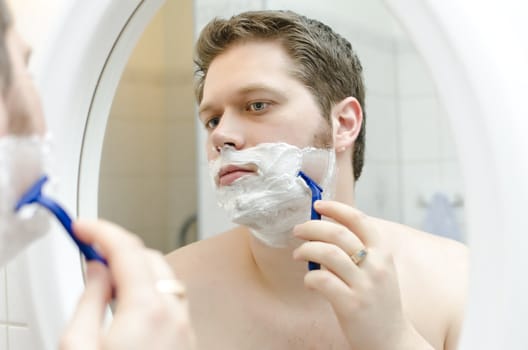 Attractive man shaving in bath room